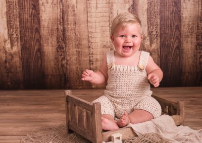 baby boy sitter on wooden bed laughing