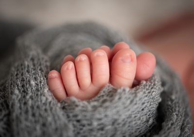 newborn baby toes wrapped in a grey layer