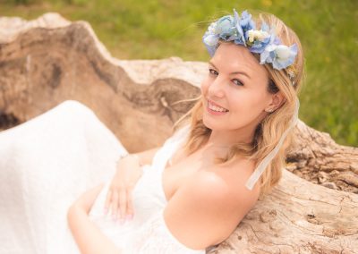outdoor maternity photo in a white dress on a log bench