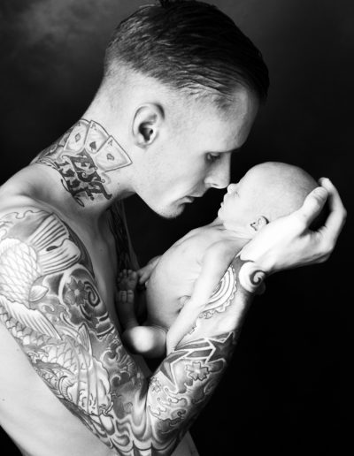 father with tattoos holding newborn baby